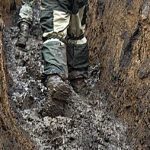 ноги бійця у брудному окопі під час війни, небезпечні умови на передовій